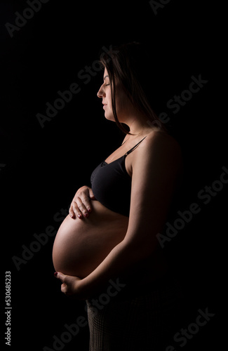 Young Brunette woman closing her eyes and holding her baby bump. © Carl