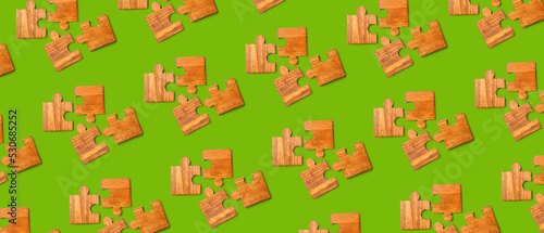 Wooden pieces of jigsaw puzzle on green background. Pattern for design