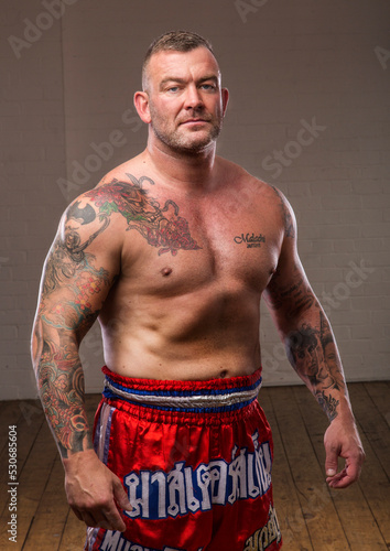 Adult male fighter stands with confidents and looks into the camera.