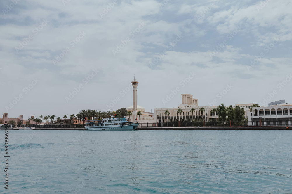 Obraz premium View of Dubai Creek channel with traditional Abra boats and piers. Famous tourist destination in UAE, United Arab Emirates. Historic Old arab town. Deira Old Souk. Artificial river length of 3 km