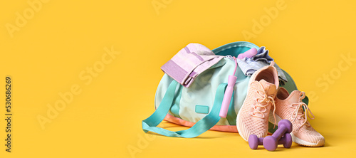 Fototapeta Naklejka Na Ścianę i Meble -  Bag with sportswear and equipment on yellow background