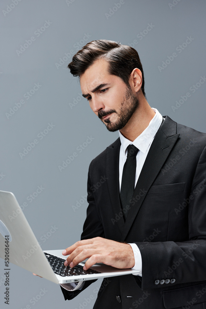 Man business looks into laptop and works thoughtfully online via internet in business suit video call business talks on gray background copy place Man business looks into laptop and works thoughtfully online via internet in business suit video call business talks on gray background copy place