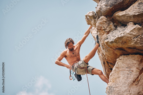Mountain or rock climbing, cliff hanging and adrenaline junkie out on adventure and checking his safety equipment, hook and rope. Fearless man doing fitness, exercise and workout during extreme sport