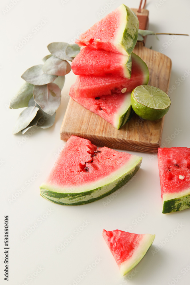 Cutting board with slices of watermelon, lime and eucalyptus branch on white background Cutting board with slices of watermelon, lime and eucalyptus branch on white background