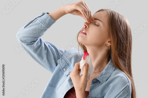 Young woman with nosebleed ...