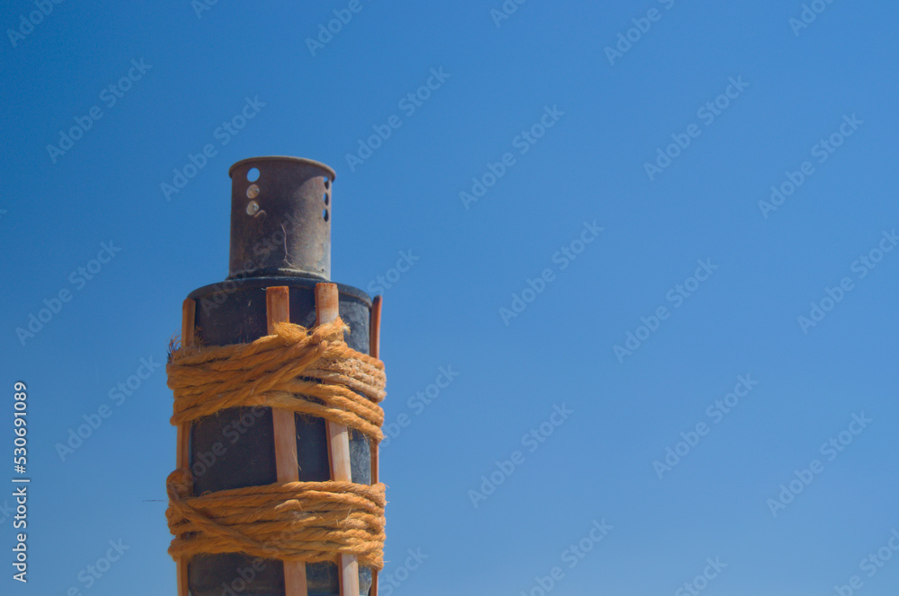 Antorcha de bambú y metal sobre fondo azul cielo