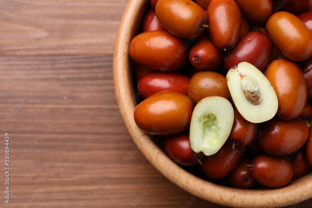 Fresh Ziziphus jujuba fruits in bowl on wooden table, top view. Space for text Fresh Ziziphus jujuba fruits in bowl on wooden table, top view. Space for text