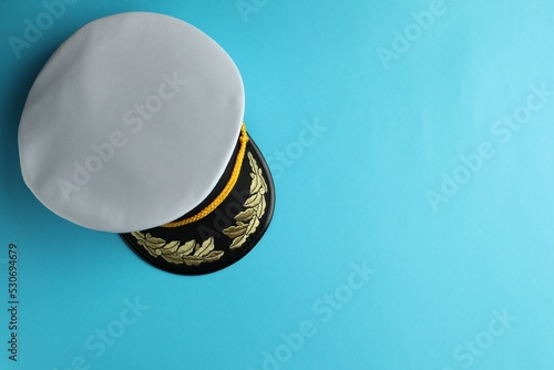 Peaked cap with accessories on light blue background, top view. Space for text photo