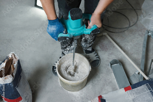Fotografie Professional worker mixing plaster in bucket indoors, closeup