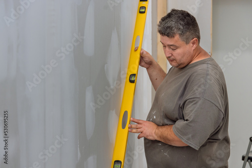 With the aid level, the employee checks equalization of drywall before it is painted