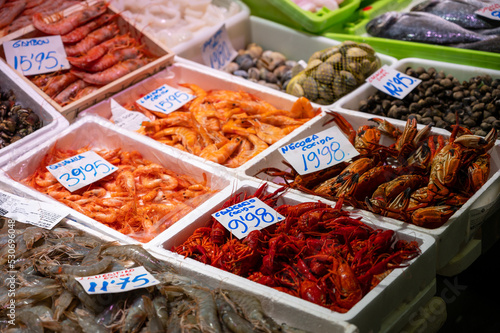 Assortment of fresh catch of fishes, seashells, molluscs on ice on fish market in Spain © barmalini