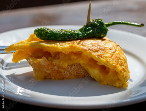 Typical snack in bars of Basque Country, pinchos or pinxtos, small slices of bread withn different toppings and fastened with skewers, San Sebastian, Spain. Potato tortilla with green pepper. photo