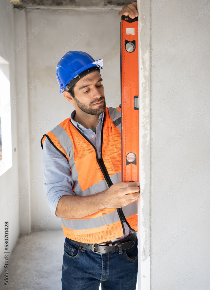 Workman engineer in overalls installing or adjusting plastic windows in the living room at home.Renovate home and build in house decoration.Professional team precision install door and windows. Workman engineer in overalls installing or adjusting plastic windows in the living room at home.Renovate home and build in house decoration.Professional team precision install door and windows.