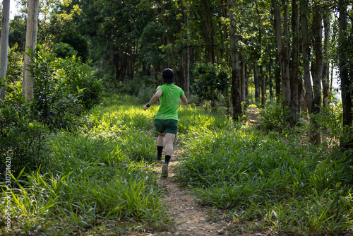 Trail runner running in summer forest trail