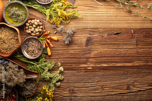 Fototapeta Naklejka Na Ścianę i Meble -  Natural medicine background. Assorted dry herbs in bowls, mortar and plants on rustic wooden table.