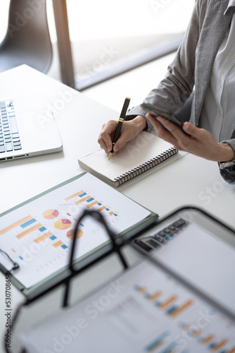 close up of businesswoman working on a document and paper and financial stock graph chart diagram.