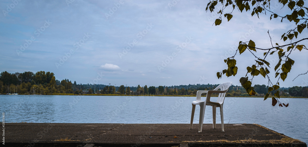Tranquil autumn landscape over the empty dock with a white chair at Union Bay near Arboretum Waterfront Trail of Foster Island, Seattle, Washington State 