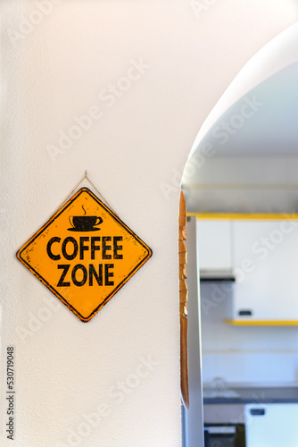 Poster hanging yellow on a wall that reads: Coffee zone