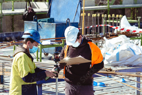 Surveyors marking up a construction deck with face masks