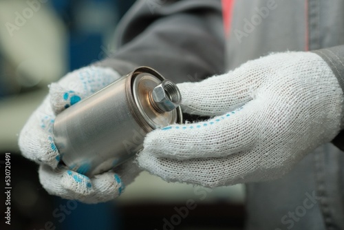 The fuel filter is new for the car engine. Close-up. An auto mechanic inspects the fuel filter, monitors the compliance and integrity of the spare part.
