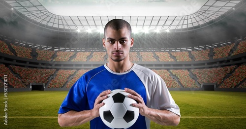 Composition of male football player holding football over sports stadium