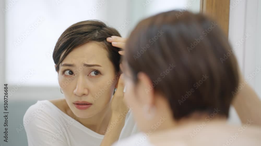 60p　洗面所で薄毛に悩むミドル女性（髪の毛・白髪）