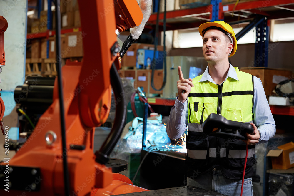 factory worker or engineer operating remote switch controller to control robot machine in the factory