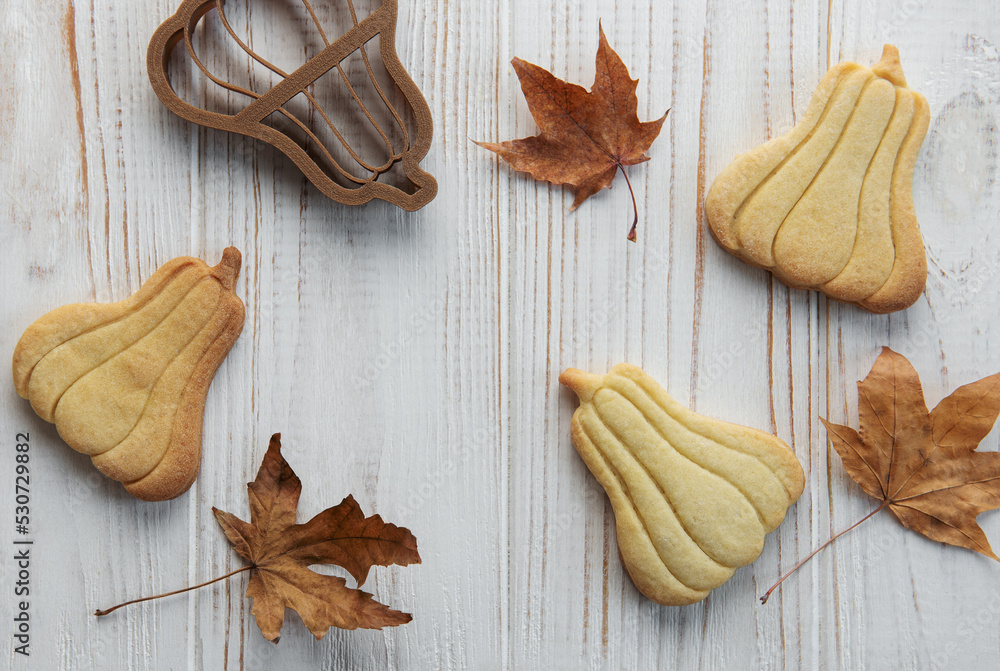 Cookies shaped like pumpkin and leaves on rustic wood background