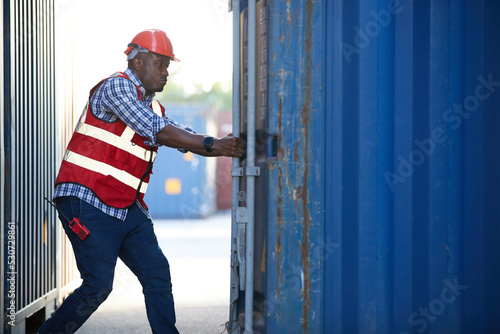 African factory worker or foreman opening the container door in warehouse storage