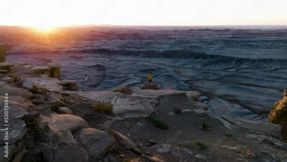 Girl Standing On Top Of Cliff Admiring The Natural And Majestic Landscape Of Utah At Sunrise In USA. - aerial Girl Standing On Top Of Cliff Admiring The Natural And Majestic Landscape Of Utah At Sunrise In USA. - aerial