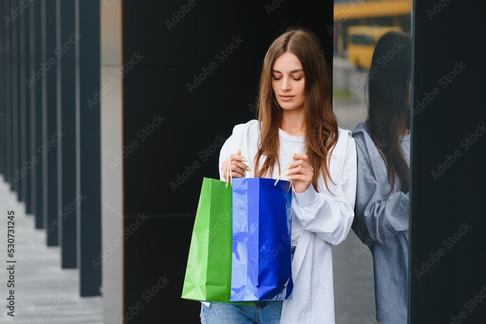 woman holding shopping bags of luxury brands, walking near shopping mall woman holding shopping bags of luxury brands, walking near shopping mall