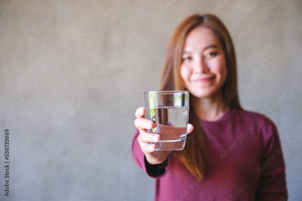 Portrait image of a young woman holding and giving a glass of water Portrait image of a young woman holding and giving a glass of water