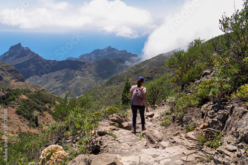 Fotografering Woman with backpack descending Pico Verde with view on the Teno mountain massif, Tenerife, Canary Islands, Spain, Europe
