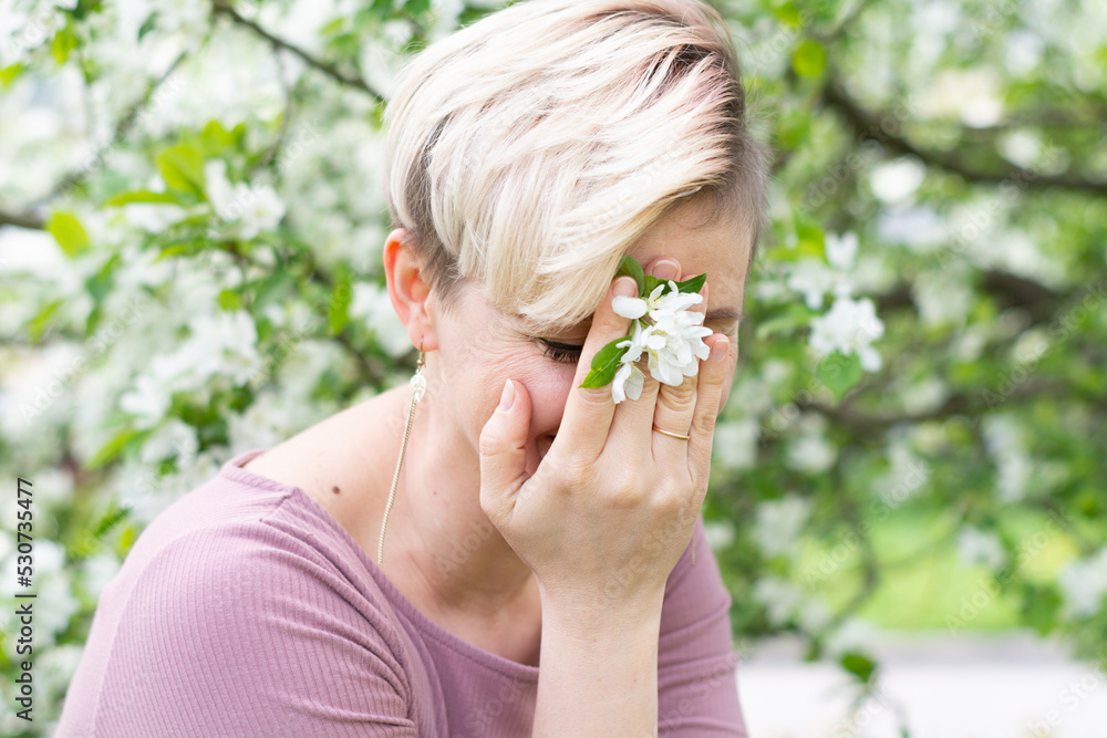 young woman with pink hair poses by a blooming apple tree. young woman with pink hair poses by a blooming apple tree.
