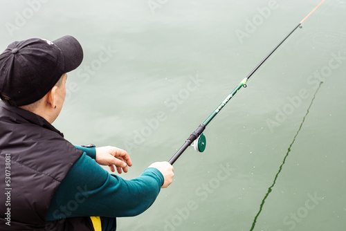 Man on a fishing rod in his hands catches fish on the river