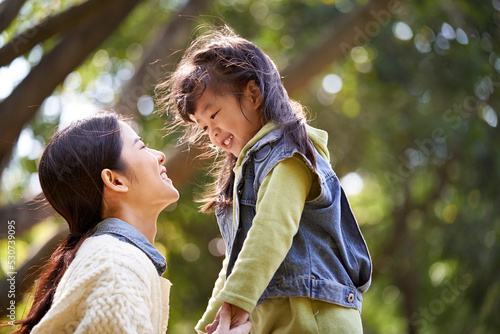 young asian mother talking to daughter outdoors in park