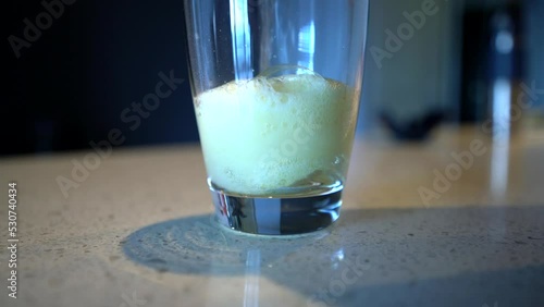 Pouring water into a tall glass with cream colored powder turning to foam photo