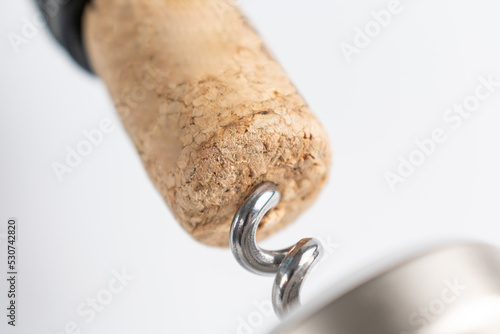 Close up of a corkscrew opening a bottle of wine. The cork is pierced by the metal spiral of the tool photo