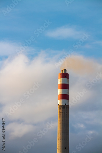 Power plant chimney on blue cloud background