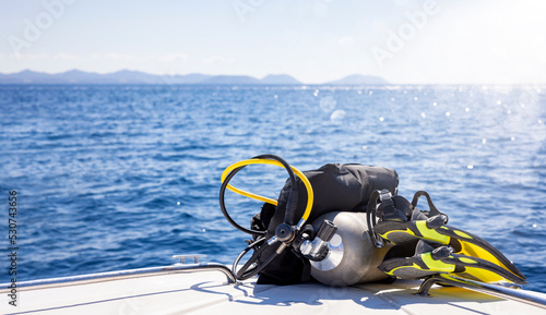 Concept of scuba diving with tank and equipment lying on a boat over blue sea and sunshine photo