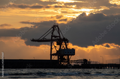 Heavy equipment crane silhouette on twilight clouds background © OYeah