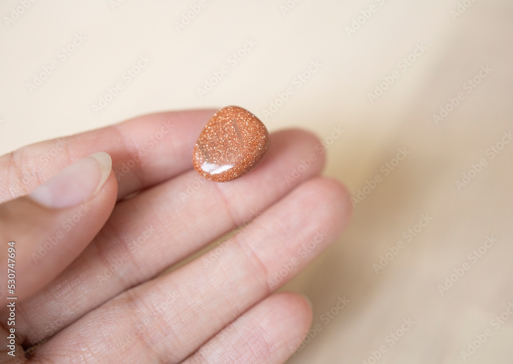 colored natural stone, aventurine on a light background, in a girl's hand. Astrology, mascot for the zodiac sign Virgo, sun stone colored natural stone, aventurine on a light background, in a girl's hand. Astrology, mascot for the zodiac sign Virgo, sun stone