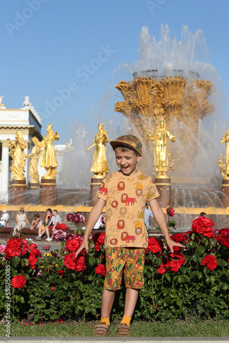 Russian tourist boy, fun child, fashion kid in Moscow city, Russia. VDNKh, Exhibition of Achievements of National Economy, Friendship of Nations fountain. Street style. Active recreation in Moscow