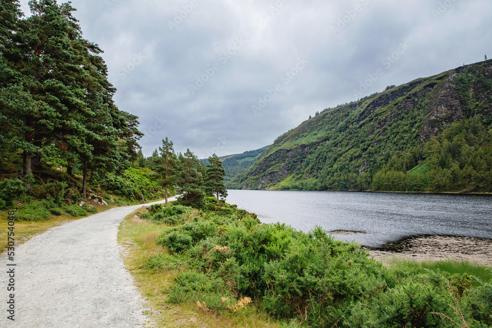 Idyllic view in Glendalough Valley, County Wicklow, Ireland. Mountains, lake and tourists walking paths Idyllic view in Glendalough Valley, County Wicklow, Ireland. Mountains, lake and tourists walking paths