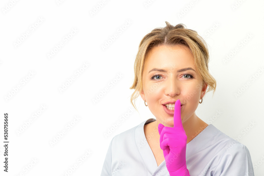 Young beautiful caucasian woman doctor, beautician doing silent gesture pressing his index finger to his lips isolated on white background Young beautiful caucasian woman doctor, beautician doing silent gesture pressing his index finger to his lips isolated on white background