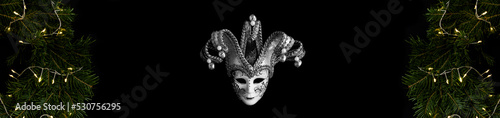 Christmas banner. Carnival venetian mask and Christmas ring or wreath on the black background. Copy space.