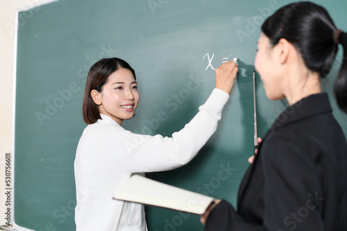 黒板に記入する女子学生と先生（講師）