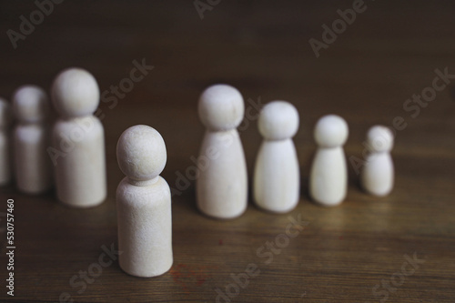Hand picking wooden figures of people on Wooden table.Personal selection