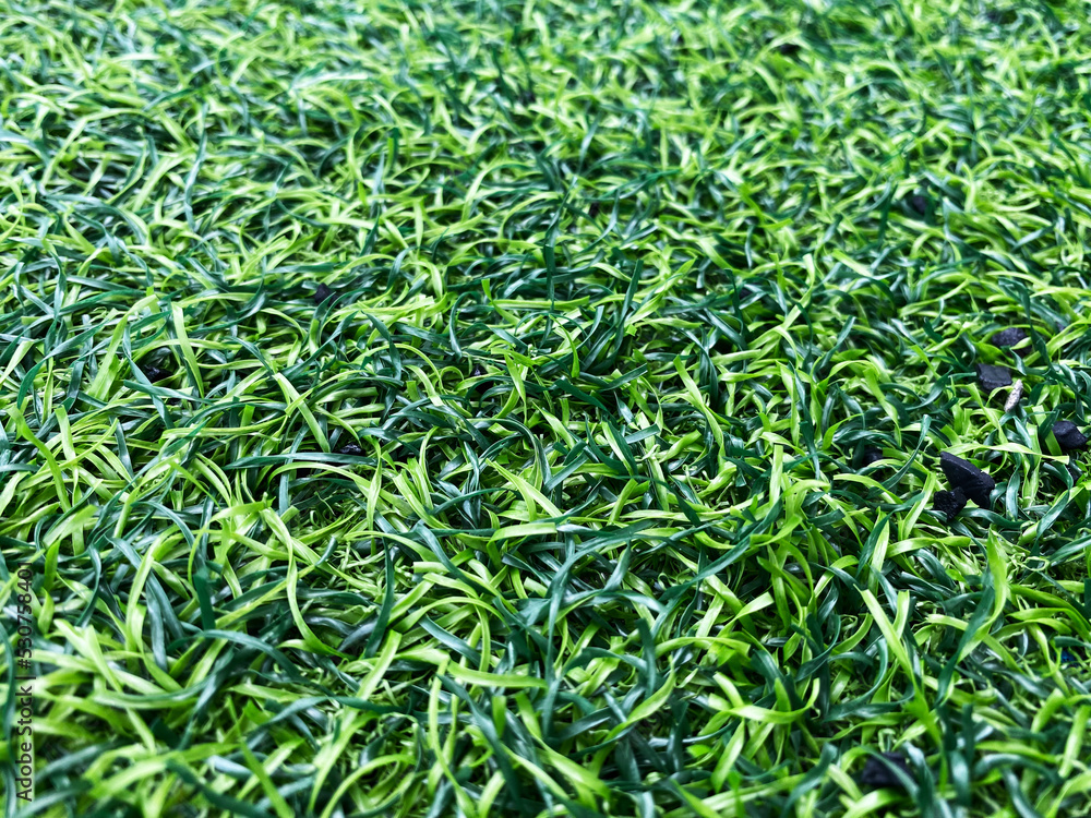 Texture of plastic artificial grass and the rubber pellets on school yard