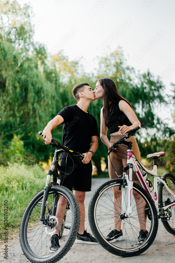 Young loving couple kissing on the bicycles